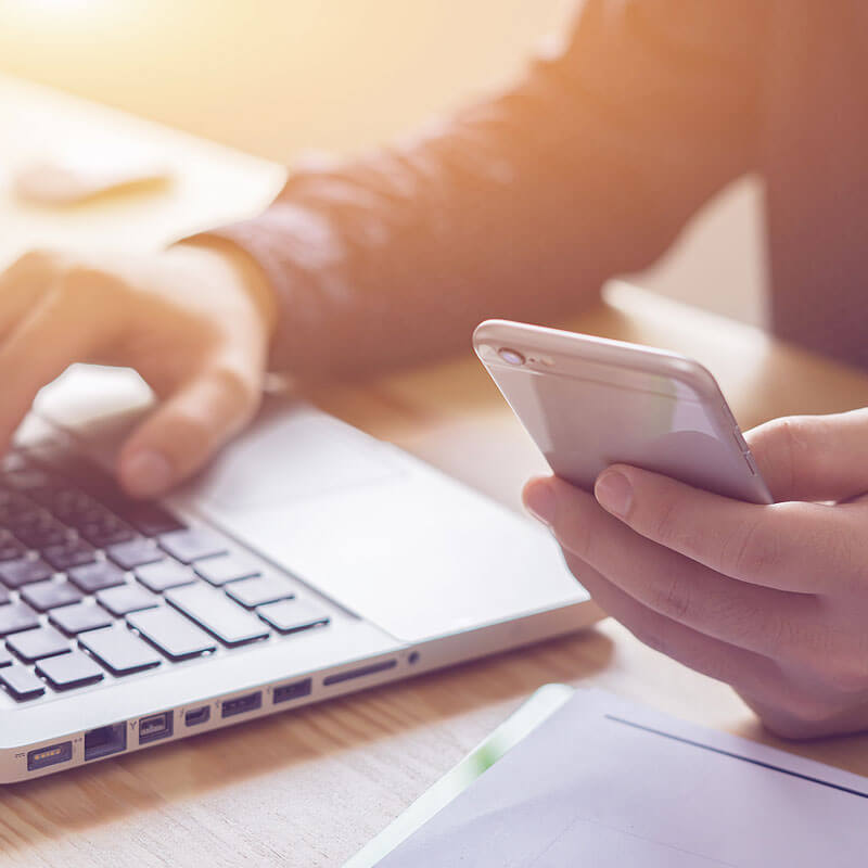 Closeup of a Man Working on a Computer and his Mobile Phone